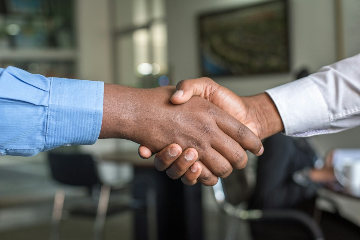 Two people shaking hands on a company ownership transfer
